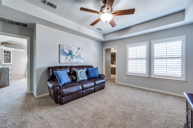 living area with carpet floors, a raised ceiling, and visible vents