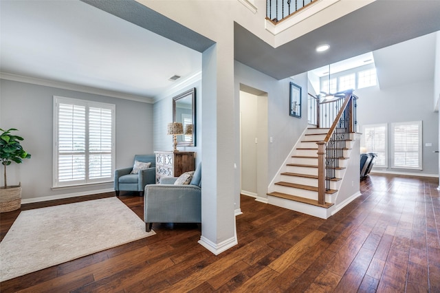 stairs with a high ceiling, baseboards, crown molding, and hardwood / wood-style floors