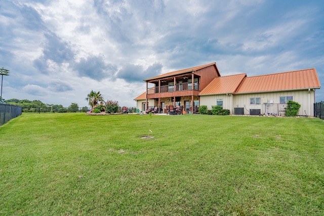 back of property with a balcony, fence, metal roof, and a yard