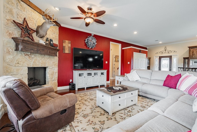 living room with light wood finished floors, baseboards, ceiling fan, crown molding, and a fireplace