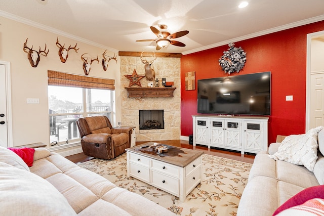 living room with light wood-type flooring, a fireplace, a ceiling fan, and crown molding