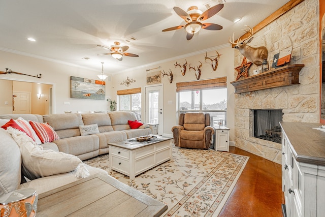 living area featuring ceiling fan, a fireplace, crown molding, and wood finished floors