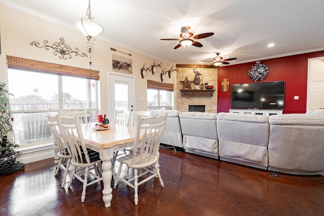 dining area featuring ceiling fan, a stone fireplace, and ornamental molding