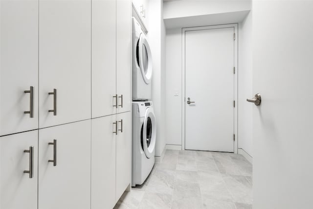 clothes washing area featuring stacked washer and dryer and cabinet space