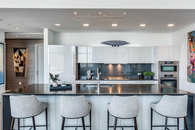 kitchen with dark countertops, modern cabinets, white cabinetry, and a sink