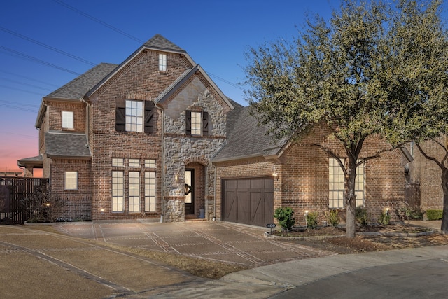 french country style house with concrete driveway, a garage, french doors, and brick siding