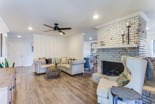 living room with a fireplace, visible vents, ornamental molding, a ceiling fan, and wood finished floors