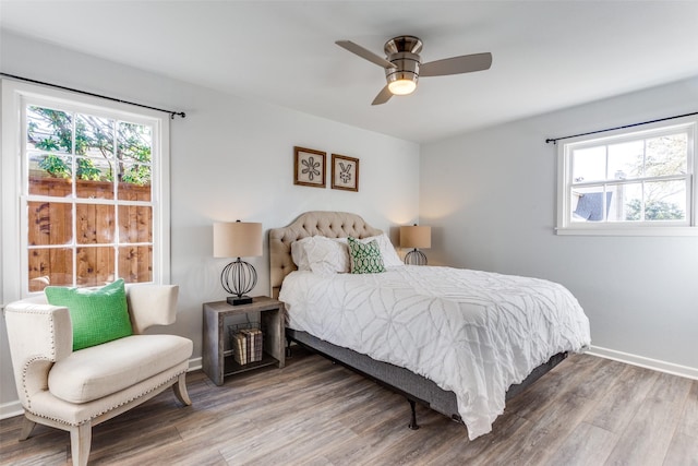 bedroom with multiple windows, wood finished floors, a ceiling fan, and baseboards