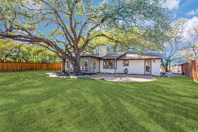 back of house featuring a patio area, fence, brick siding, and a lawn