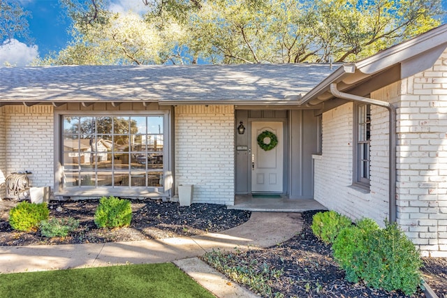 property entrance with brick siding and roof with shingles