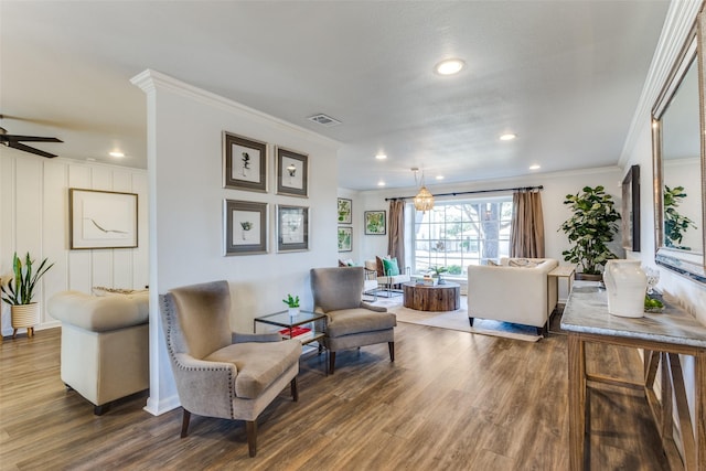 living room with wood finished floors, visible vents, and crown molding