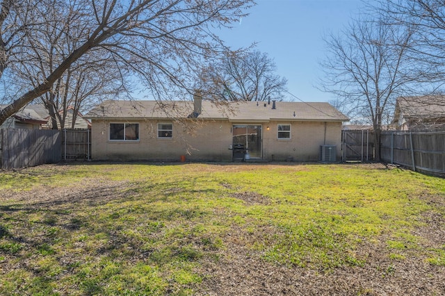 back of property with a yard, brick siding, and a fenced backyard