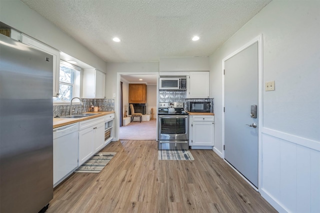 kitchen with light wood-style floors, white cabinetry, appliances with stainless steel finishes, and a sink