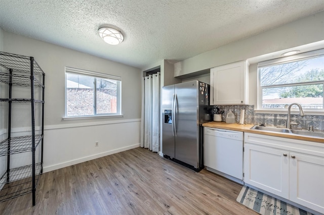 kitchen featuring light wood-style flooring, white cabinetry, a sink, stainless steel fridge, and dishwasher