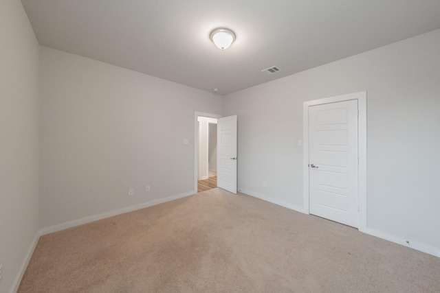 unfurnished room with baseboards, visible vents, and light colored carpet