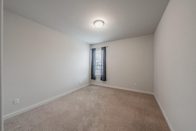 unfurnished room featuring light carpet and baseboards