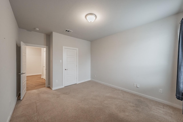 unfurnished bedroom with light colored carpet, a closet, visible vents, and baseboards