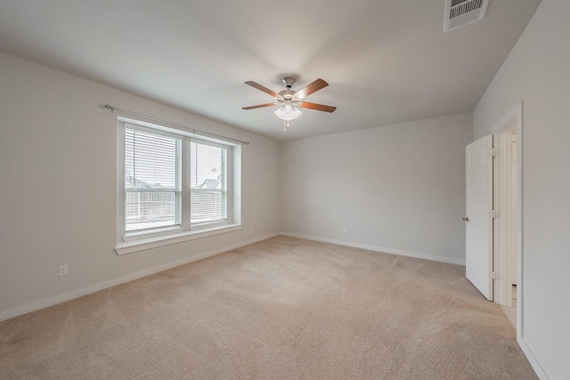 unfurnished room featuring baseboards, visible vents, a ceiling fan, and light colored carpet