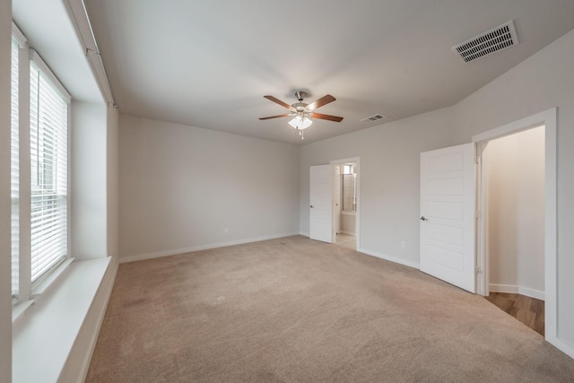 interior space featuring light carpet, ensuite bath, visible vents, and baseboards