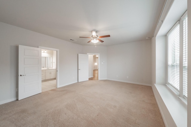 unfurnished bedroom featuring baseboards, visible vents, a ceiling fan, light colored carpet, and ensuite bathroom