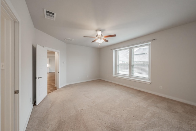 unfurnished room with ceiling fan, visible vents, and light colored carpet