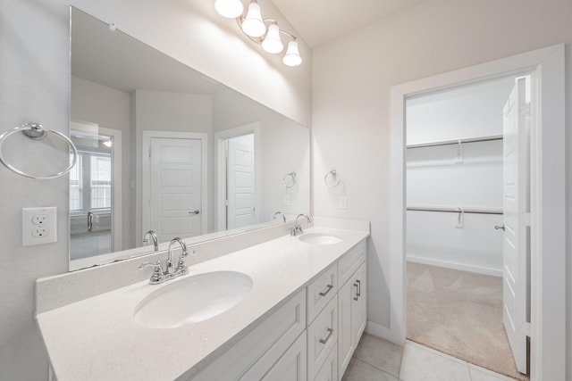 full bathroom with double vanity, tile patterned floors, a sink, and baseboards