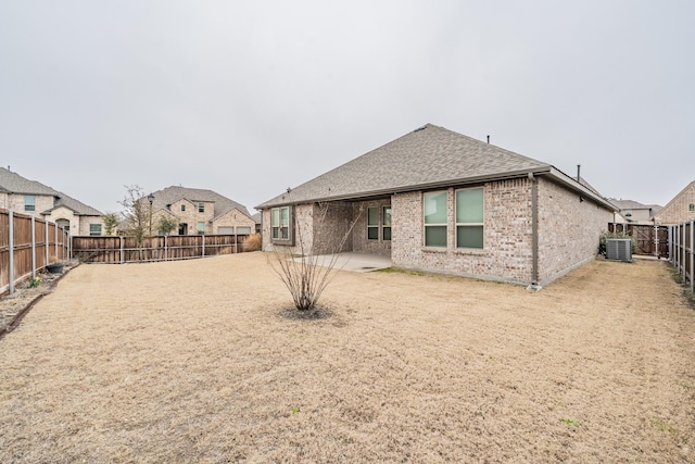 rear view of house featuring a patio, a fenced backyard, central air condition unit, brick siding, and roof with shingles