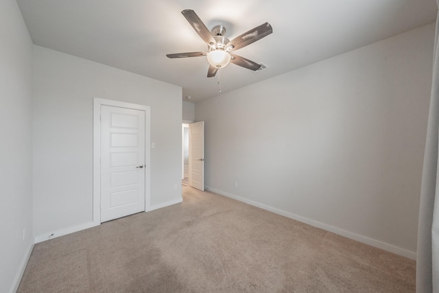 unfurnished bedroom with a ceiling fan, light carpet, and baseboards