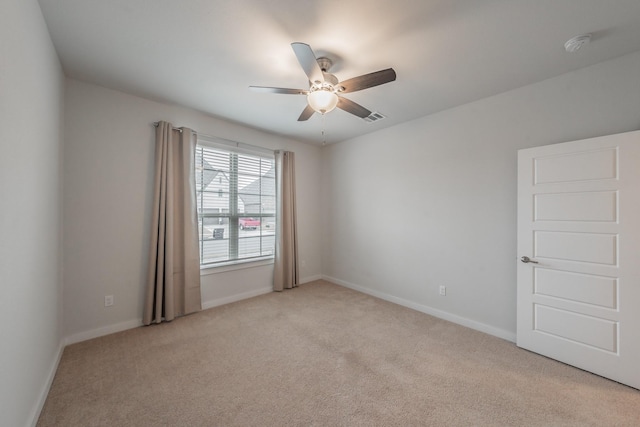 empty room with a ceiling fan, carpet flooring, visible vents, and baseboards