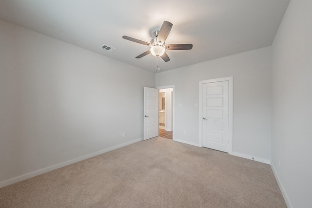 empty room featuring light carpet, a ceiling fan, visible vents, and baseboards