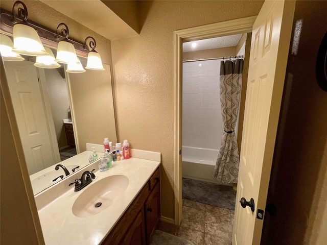 bathroom with a textured wall, shower / tub combo with curtain, and vanity