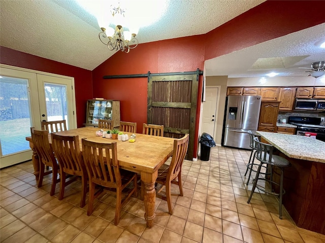 dining area with vaulted ceiling, a barn door, and a textured ceiling