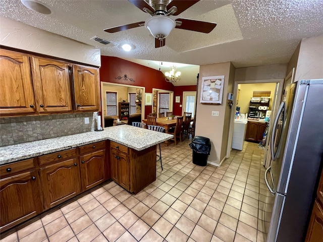 kitchen with light tile patterned floors, tasteful backsplash, visible vents, freestanding refrigerator, and a peninsula