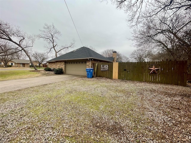 view of side of property featuring brick siding, driveway, an attached garage, and fence