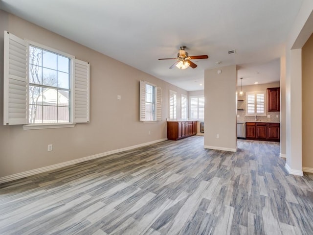 unfurnished living room featuring visible vents, wood finished floors, a ceiling fan, and baseboards