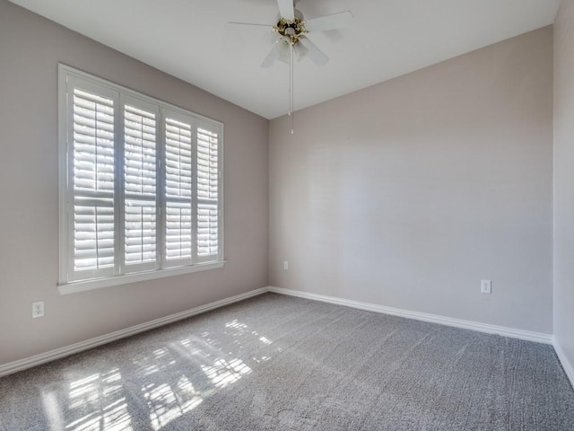 carpeted spare room featuring ceiling fan and baseboards