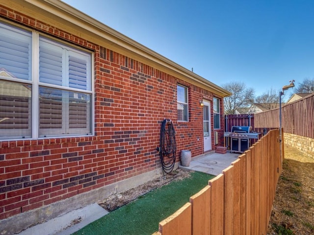 view of property exterior with brick siding and fence