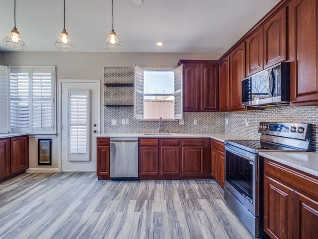 kitchen with light wood-style flooring, backsplash, stainless steel appliances, light countertops, and a sink