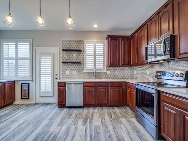 kitchen featuring light wood finished floors, stainless steel appliances, light countertops, open shelves, and a sink