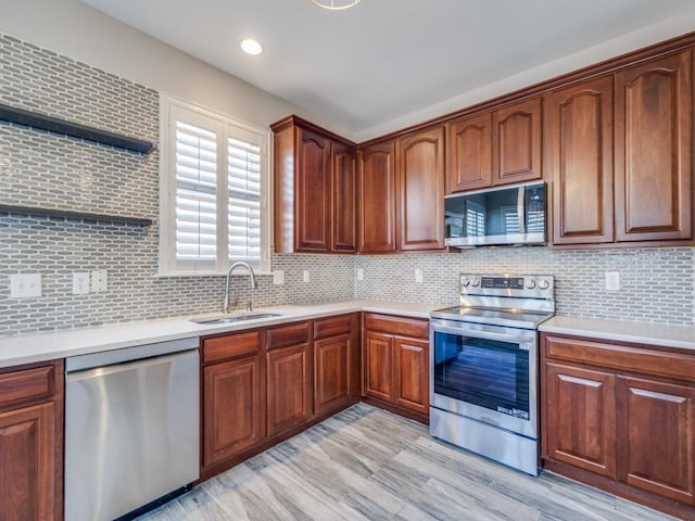 kitchen with light wood finished floors, stainless steel appliances, light countertops, backsplash, and a sink