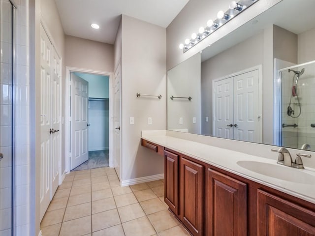 bathroom featuring vanity, baseboards, tiled shower, and tile patterned floors