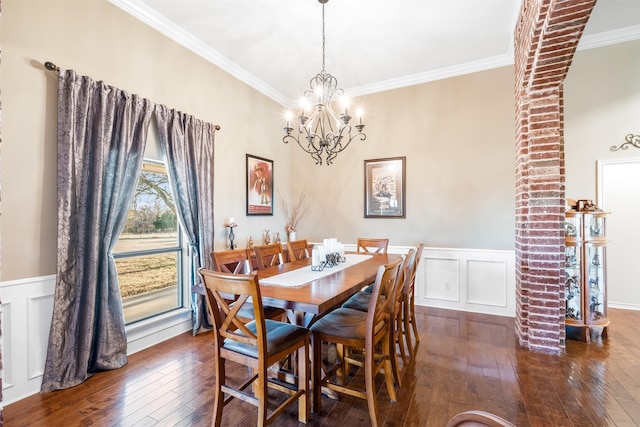 dining room with a wainscoted wall, a decorative wall, ornamental molding, a chandelier, and hardwood / wood-style flooring