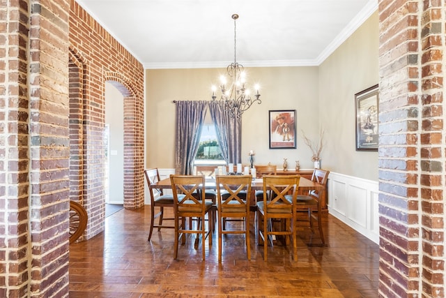 dining area with a wainscoted wall, a chandelier, crown molding, and hardwood / wood-style floors