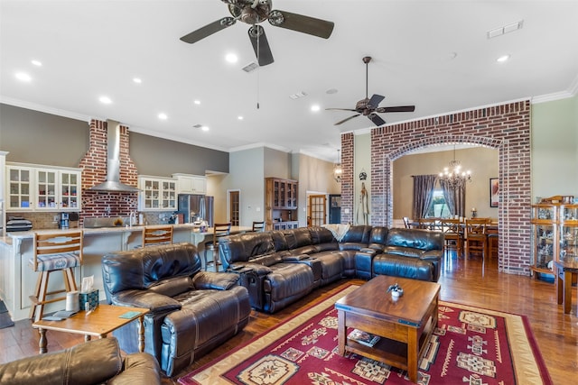 living room with crown molding, visible vents, arched walkways, and wood finished floors