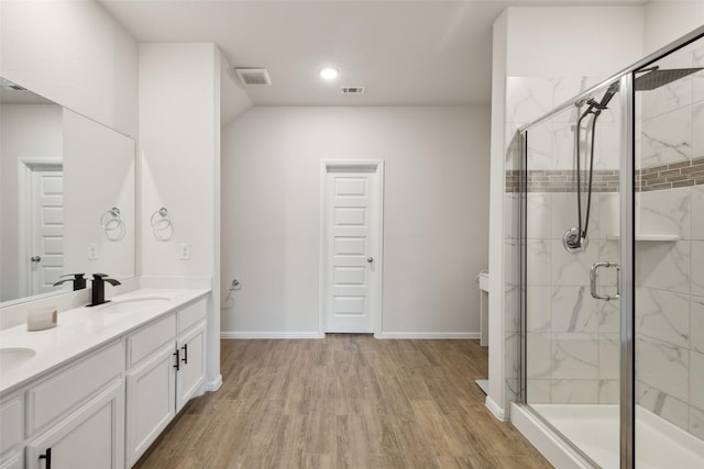 full bathroom featuring visible vents, a sink, a shower stall, and wood finished floors