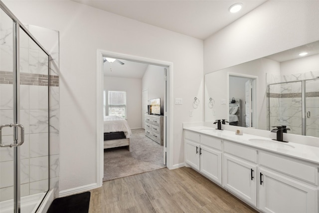 ensuite bathroom with ensuite bathroom, wood finished floors, a stall shower, and a sink