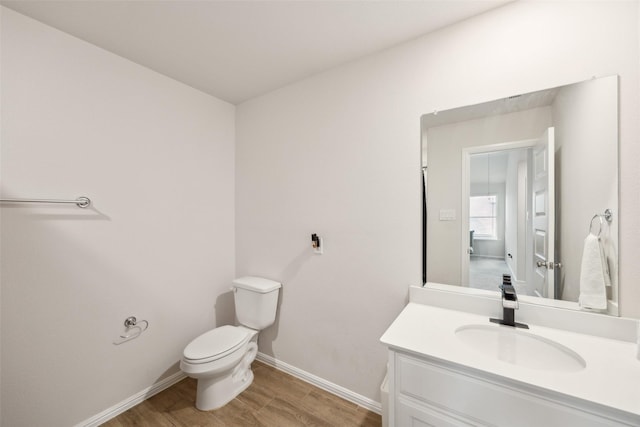 bathroom with baseboards, vanity, toilet, and wood finished floors