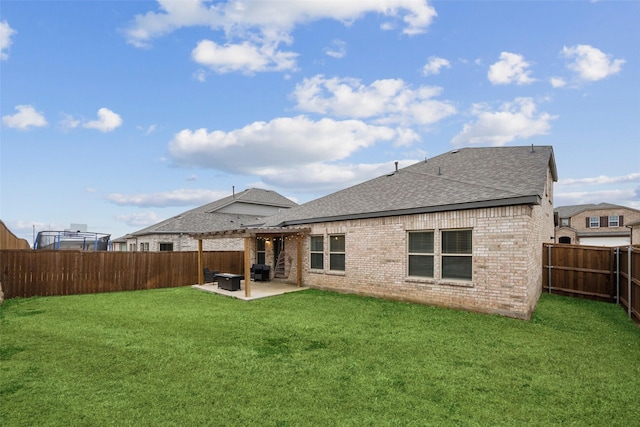 rear view of property with a fenced backyard, brick siding, roof with shingles, a lawn, and a patio area