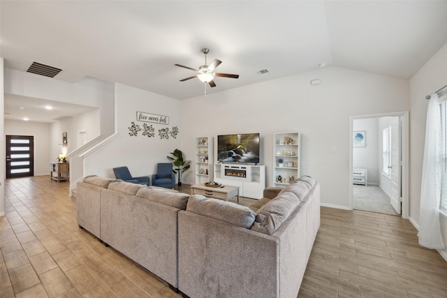 living room with a ceiling fan, light wood-type flooring, visible vents, and lofted ceiling