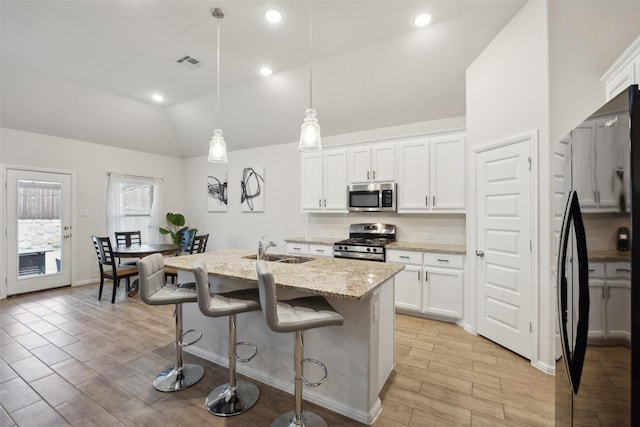 kitchen with visible vents, appliances with stainless steel finishes, light stone countertops, vaulted ceiling, and a sink